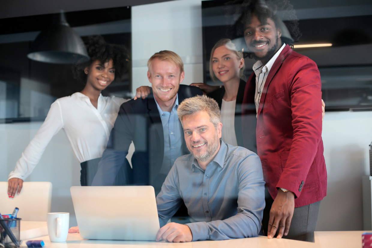 Fotografia apresenta um grupo de pessoas reunidas em frente a um computador.